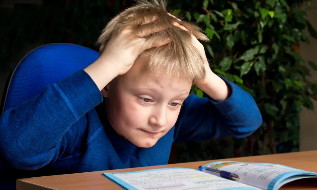 پسربچه کلافه جلوی دفتر مشق